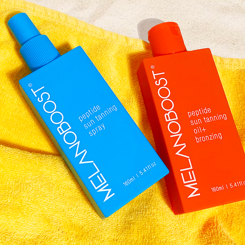 orange_and_aqua_Melanoboost_Peptide_Tan_accelerator_Sun_Tanning_Oil_and_spray_lying_on_yellow_beach_towel