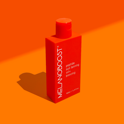 Orange_bottle_of_Melanoboost Peptide_Sun_Tan_Accelerator_Oil_Bronzing_on_a_lighter_orange_background