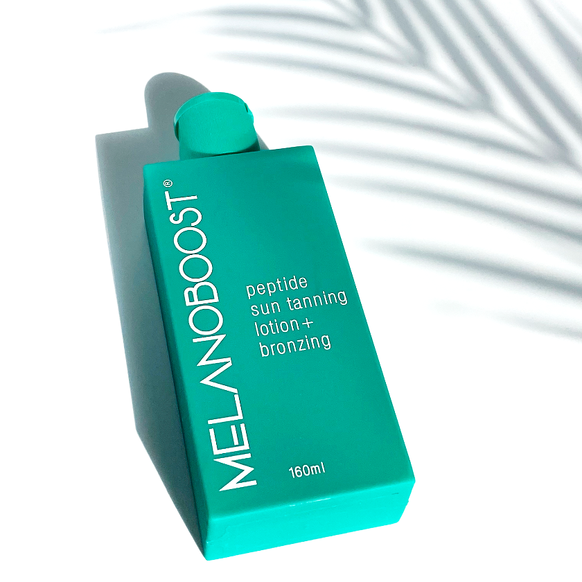 green_bottle_of_Melanoboost_Peptide_Sun_Tan_Accelerator_Lotion_Bronzing_on_a_white_background_with_palm_leaf_shaddow