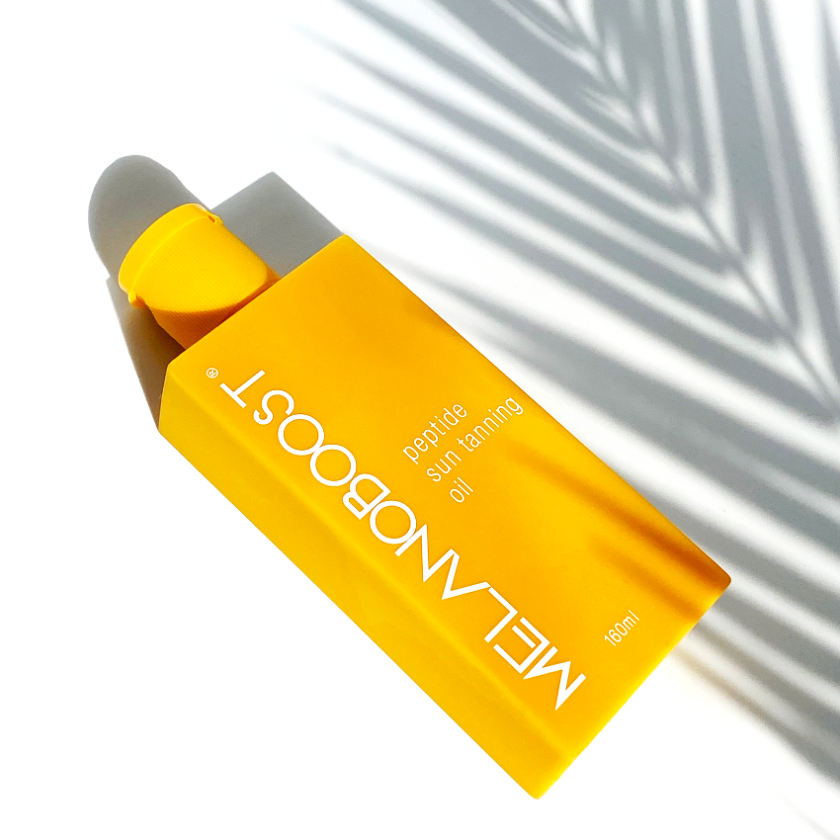 yellow_Melanoboost_Peptide_Sun_Tan_Accelerator_Oil_bottle_against_a_white_background_with_palm_leaf_shadow
